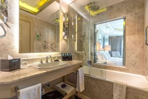 a bathroom with a sink and a tub and a mirror at Wyndham Grand Istanbul Kalamış Marina Hotel in Istanbul