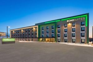 a large building with a green sign on it at ECHO Suites Extended Stay by Wyndham Madison in Madison