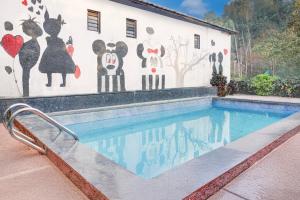 um mural na lateral de um edifício com piscina em Hotel O Malavli Lonavala Hill View em Lonavala