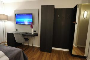 a bedroom with a desk and a tv on a wall at Hotel B99 in Offenbach