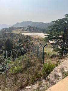 una recinzione di filo spinato su una collina con un campo di Moonwind, two bedroom apartment with sitting room and Kitchenette a Mussoorie