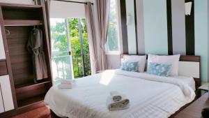 une chambre avec un grand lit blanc avec une fenêtre dans l'établissement Villa Rajapruek Private Villa 3 houses combine near Airport, à Chiang Mai 67 autres photos