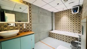 a bathroom with a sink and a mirror and a tub at The Garden Hotel in Ahmedabad