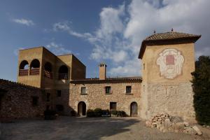 un grande edificio in pietra con una torre e un orologio di Mas la Planella Masia de Turismo Rural a Montblanc