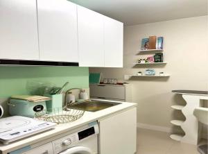 a kitchen with white cabinets and a sink and a dishwasher at Cozy Studio with Balcony and Pool View in Lapu Lapu City