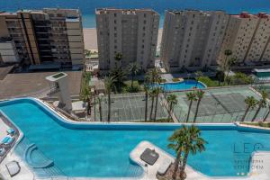 a large swimming pool with palm trees and buildings at Sunset Cliffs Apartment by Leo Apartments Benidorm in Benidorm