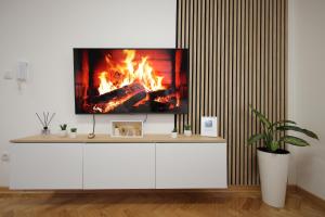 ein Fernseher auf einem weißen Schrank mit einem Kamin in der Unterkunft Apartman Babić Lux in Vrnjačka Banja