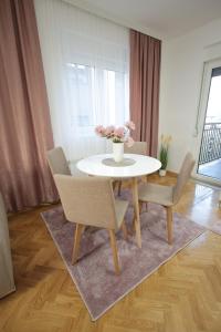 ein Esszimmer mit einem weißen Tisch und Stühlen in der Unterkunft Apartman Babić Lux in Vrnjačka Banja