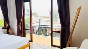 a bedroom with a bed and a balcony with a view at Vang's Homestay - Huế in Ấp Long Hồ Hạ