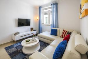a living room with a white couch and a tv at Apt. À Porta in Lagos