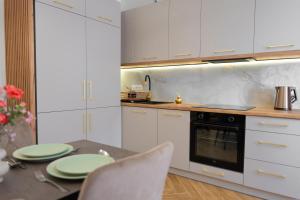a kitchen with white cabinets and a table with green plates at COCO Old Town in Kielce +21 photos