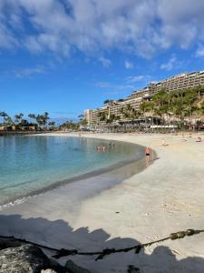 a beach with a group of people in the water at PURA VIDA Beach Suite in Arguineguín