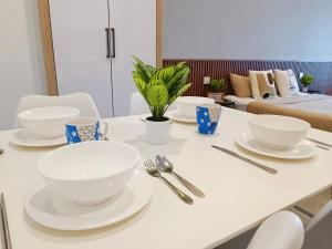 a table with white bowls and utensils on it at Imperio Melaka Standard Suites by Jeffery Lam Home Management in Melaka