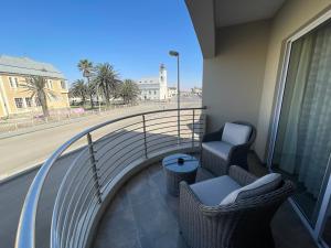 a balcony with two chairs and a view of a street at Central Cozy Apartment at Ane court in Swakopmund