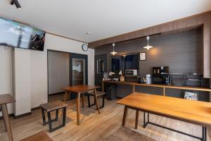 ein Zimmer mit Holztischen und einer Küche in der Unterkunft Bear Elephant in Rausu