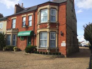 a red brick building with a green door at Fairways Guest House in Cambridge