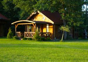 a log cabin with a porch in the grass at Oaza Ławki in Ryn