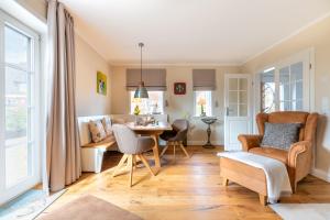 Una sala de estar con una mesa y sillas y un sofá. en FriesenLodge, en Utersum