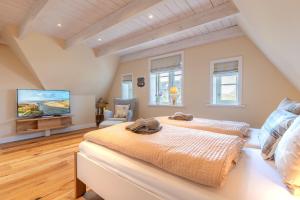 Un dormitorio con una cama grande y un televisor de pantalla plana. en FriesenLodge, en Utersum