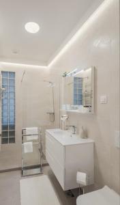 a white bathroom with a sink and a shower at Premium DC Apartment Osijek in Osijek