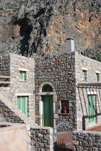 a stone building with a green door in front of a mountain at Petra Boutique Homes in Aryinónda