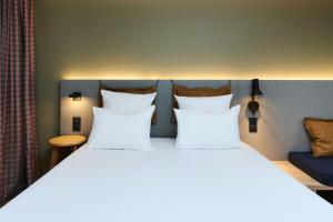 a bed with white pillows in a room at Moxy Annecy in Annecy