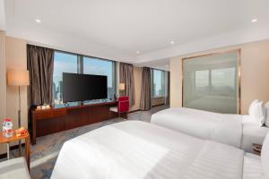 a hotel room with two beds and a flat screen tv at Novotel Atlantis Shanghai - Enjoy our great-valued breakfast in our rooftop revolving restaurant with a stunning river view & utilize our FREE self-serviced laundry in Shanghai