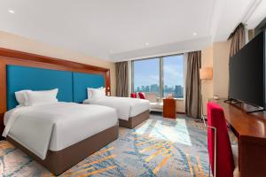 a hotel room with two beds and a flat screen tv at Novotel Atlantis Shanghai - Enjoy our great-valued breakfast in our rooftop revolving restaurant with a stunning river view & utilize our FREE self-serviced laundry in Shanghai