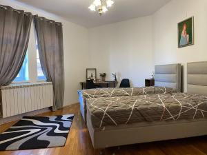 a bedroom with a bed and a desk and a window at Diplomat Haven in Sremska Kamenica