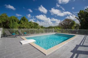 a pool on a patio with two chairs and a fence at Ti Mango - A 15min à pied de la Plage in Les Trois-Îlets