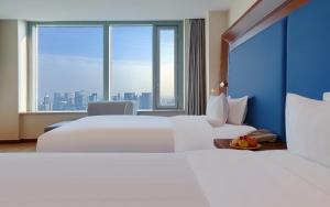 two beds in a hotel room with a large window at Novotel Atlantis Shanghai - Enjoy our great-valued breakfast in our rooftop revolving restaurant with a stunning river view & utilize our FREE self-serviced laundry in Shanghai