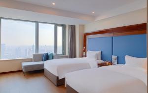 a hotel room with two beds and a large window at Novotel Atlantis Shanghai - Enjoy our great-valued breakfast in our rooftop revolving restaurant with a stunning river view & utilize our FREE self-serviced laundry in Shanghai