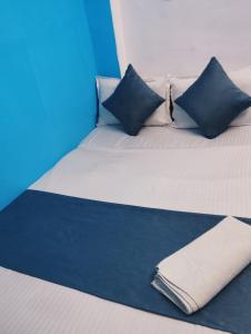 Cama blanca con almohadas azules y manta azul en Hotel Sarovar Inn, en Ahmedabad