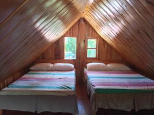 two beds in a room in a log cabin at Døng-elays Homestay in Maligcong