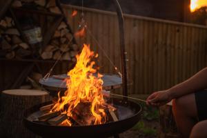Eine Person kocht über einem Feuer im Grill in der Unterkunft Stags head Safari Tents in Abbotskerswell