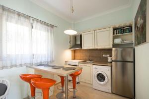 a kitchen with a table and two orange stools at White House Apartment in Kalami
