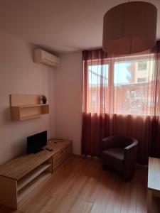 sala de estar con TV, silla y ventana en Aparthotel Salena, en Sunny Beach
