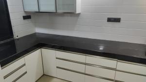 Una cocina con gabinetes blancos y una encimera negra. en Cozy 1BHk with Stunning Riverview, en Dāpuri