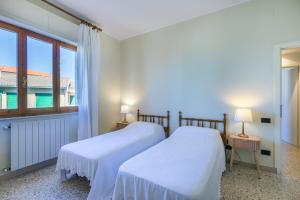 two beds in a room with a window at Italianway - Rossetti 3 in Marina di Cecina