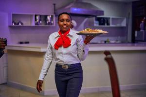 Eine Frau mit Fliege, die einen Teller mit Essen hält in der Unterkunft orlando cottages in Arusha + 6 Fotos