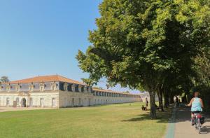 Eine Frau, die vor einem Gebäude Fahrrad fährt. in der Unterkunft Le Ferney - Proche du centre-ville et des thermes in Rochefort
