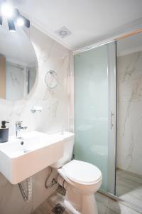 a white bathroom with a sink and a toilet at Eros appartments in Kalamitsi