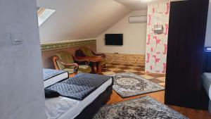 a room with two beds and a tv and chairs at Hotel i Apartamenty Rosa in Przemyśl