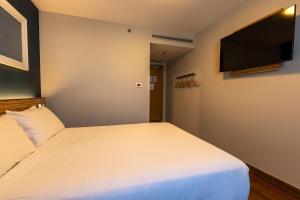 a bedroom with a white bed and a flat screen tv at Travelodge Barcelona Poblenou in Barcelona