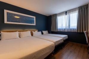 a hotel room with two beds and a window at Travelodge Barcelona Poblenou in Barcelona