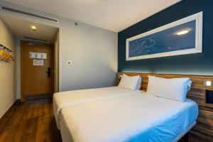 a bedroom with a large white bed and a blue wall at Travelodge Barcelona Poblenou in Barcelona