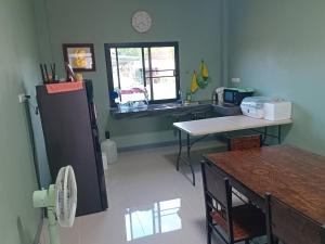 a kitchen with a refrigerator and a table and a window at Fairy Resort - แฟรี่รีสอร์ท in Ban Tha Thon