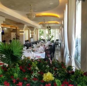 a dining room with tables and chairs and flowers at Guest House Erzeni in Tirana