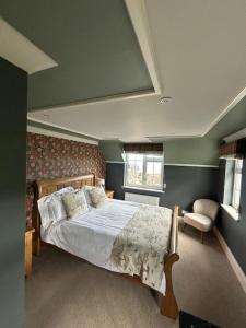 a bedroom with a large bed and a chair at Bryn Goleu Bed & Breakfast in Llandudno
