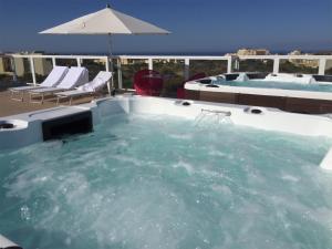 a jacuzzi tub with chairs and an umbrella at GozoWindmill Apartments in Qala